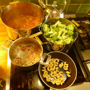 Van onder naar boven: de geroosterde cashewnoten, de ui waarin straks de rijst komt; de gestoomde broccoli en de pruttelende curry.